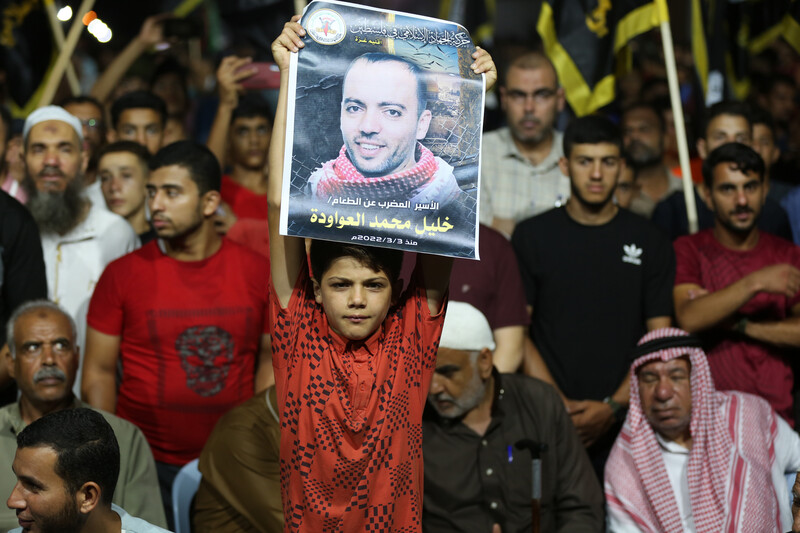 A child holds up a poster of a man 