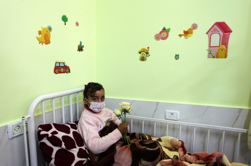 A child in a face mask lies on a hospital bed at the Rantisi Hospital in Gaza.