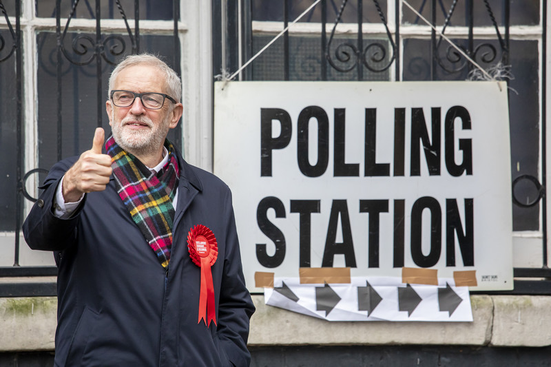 A man gives a thumbs up standing next to a polling station