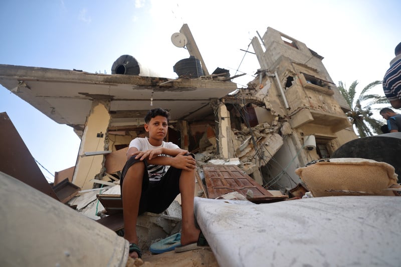A child sits atop the rubble of a destroyed building in Gaza
