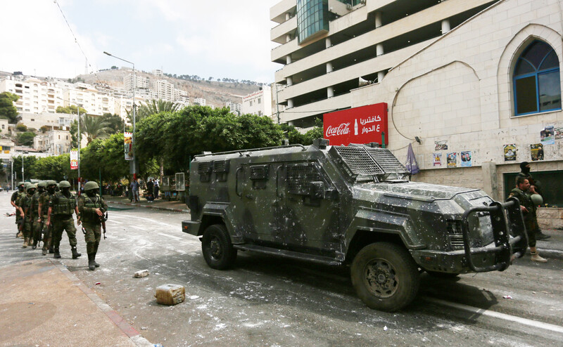 Armed forces walk by armored vehicle 