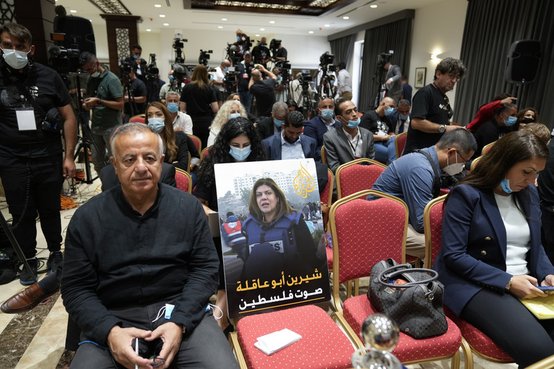 A poster on a chair in a room crowded with journalists