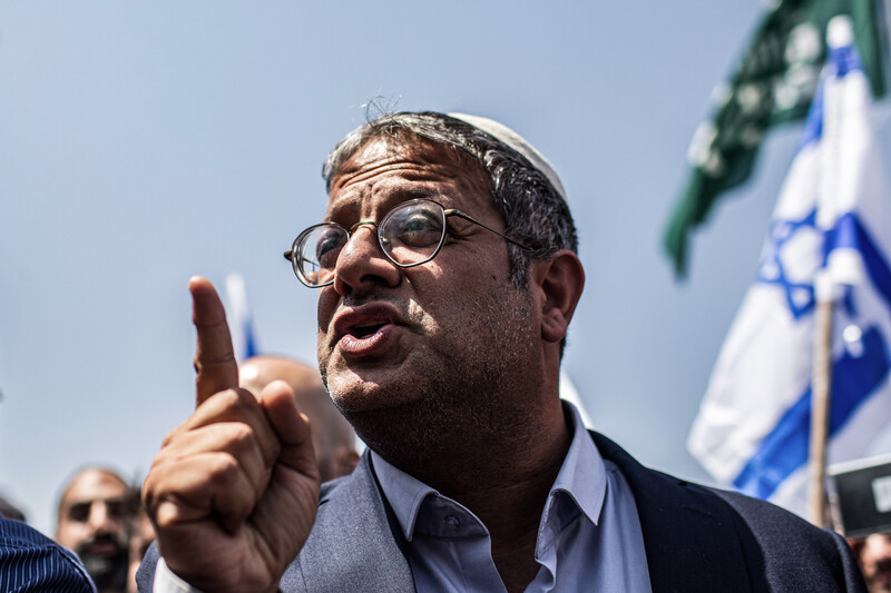 A man points with an Israeli flag behind him