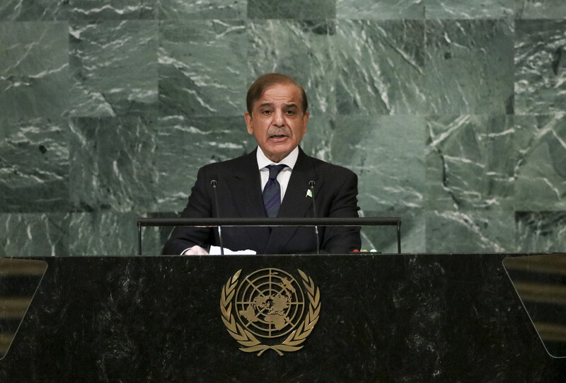 Man stands at a podium with a backdrop of green stone behind him 