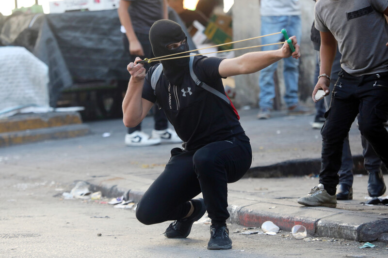 A masked man aims a slingshot