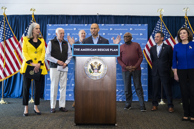 Man speaks from podium with several people looking on