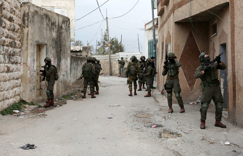 Heavily armed soldiers search between buildings
