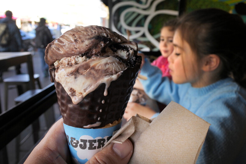 Close up of an ice cream cone with children behind it