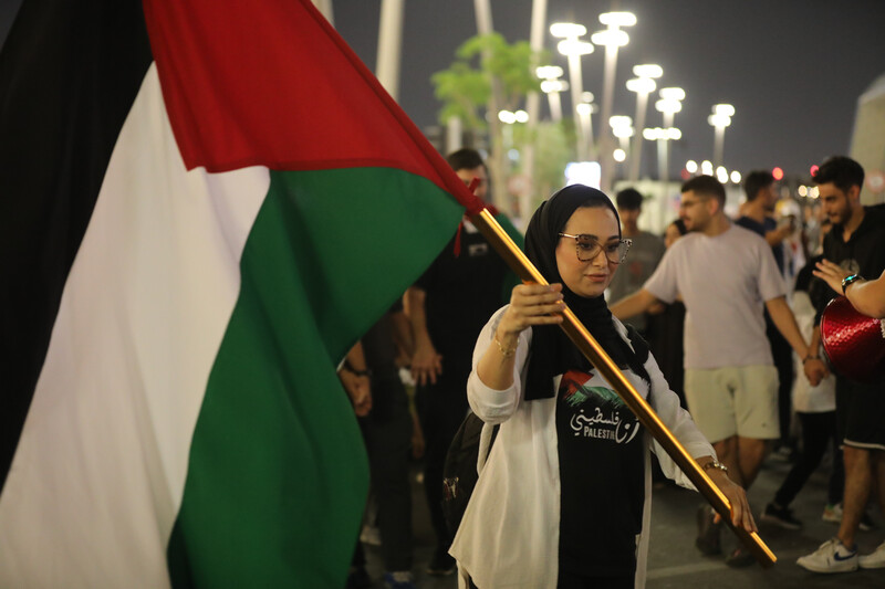 A woman in a crowd carries the Palestinian flag