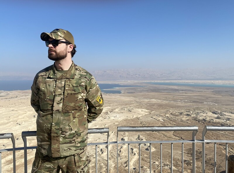 A man in military uniform overlooks a desert