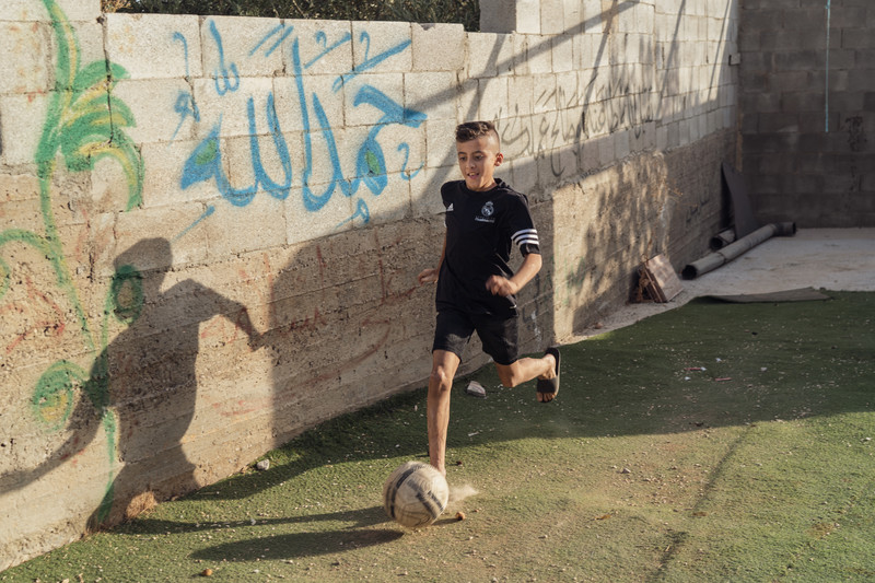 A boy runs with a football at his feet