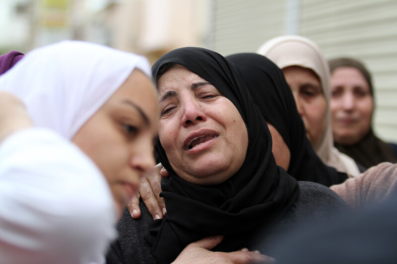 Women wearing headscarves crying and comforting each other 