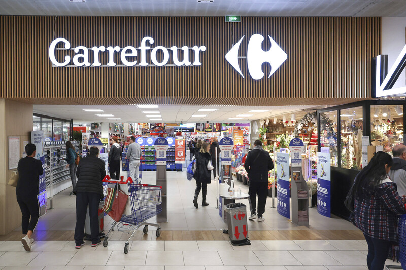 People walk in and out of the entrance of a Carrefour supermarket