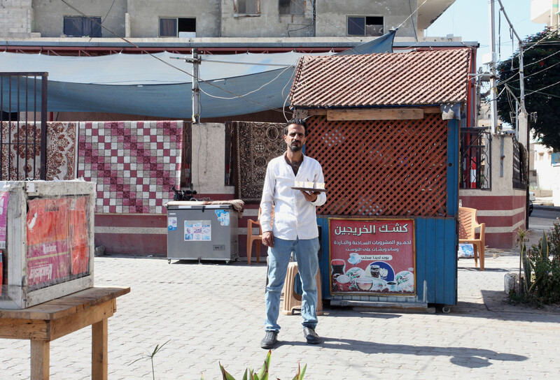 A man stands with a tray in front of a small wooden booth