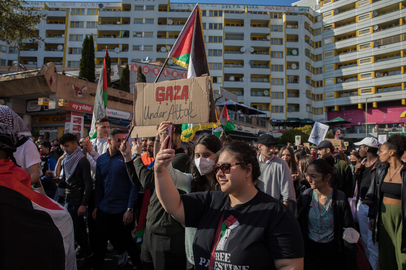 People march in a busy street with Palestinian flags and signs