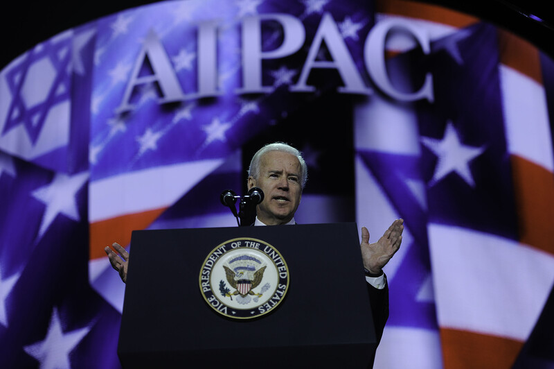 Joe Biden speaks before screen showing AIPAC's name and American and Israeli flags