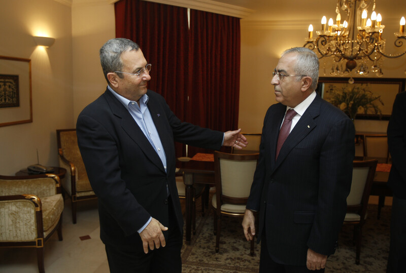 Ehud Barak and Salam Fayyad, both wearing suits, stand facing each other.