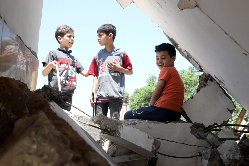 Children play in the rubble of a destroyed house.