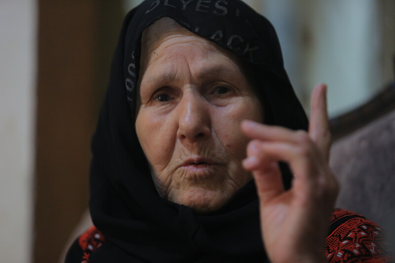 An elderly woman gesticulates with her finger