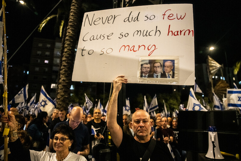 Demonstrators hold up a placard excoriating Israel's leaders for doing "so much harm to so many."