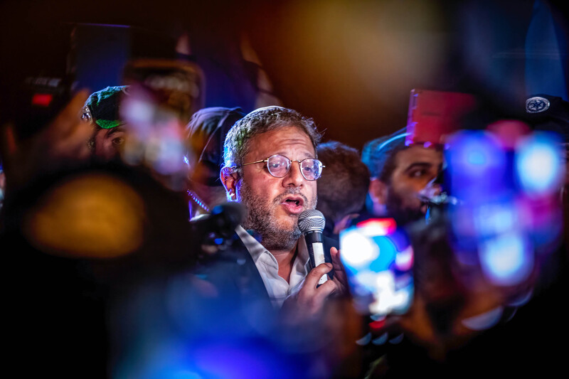 Man surrounded by demonstrators speaks into a microphone