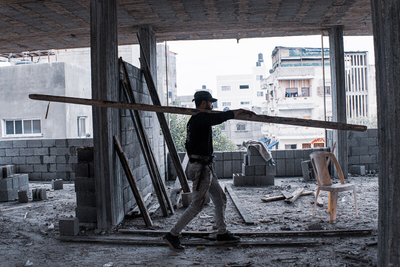 A man carries a wooden beam