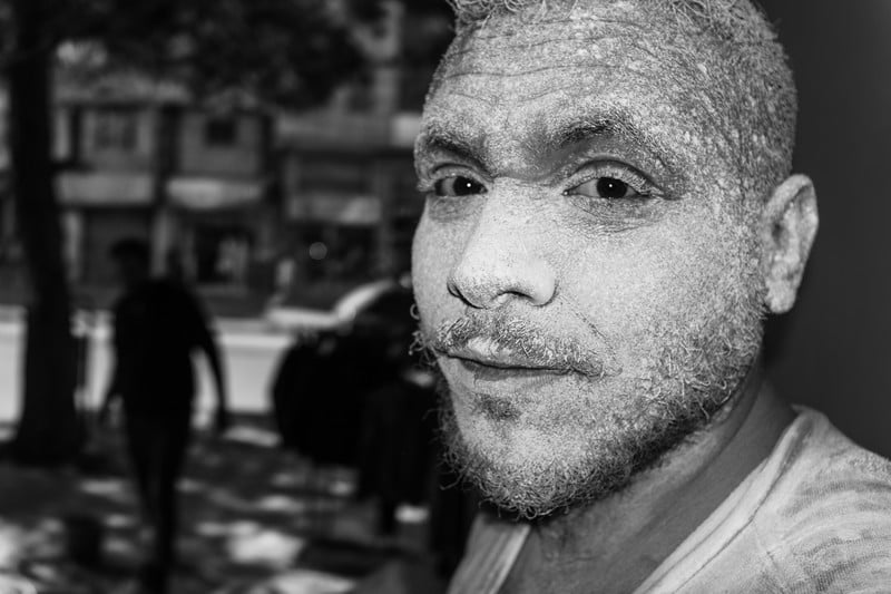 A man looks at the camera covered in dust and paint