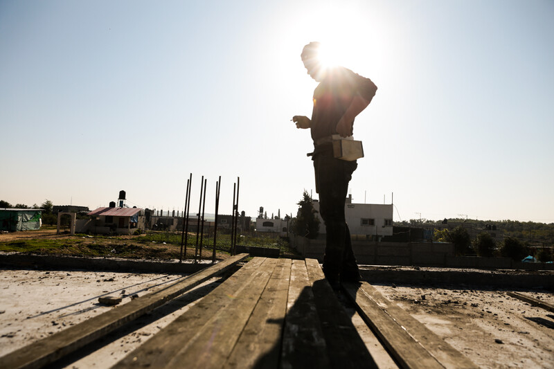 A man smokes atop several wooden beams