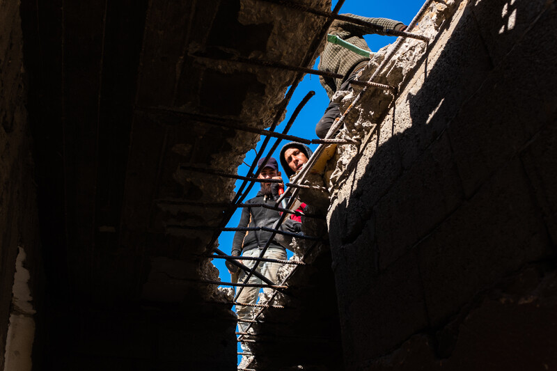 Workers look through a gap in the roof