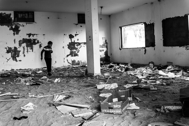 A boy looks at the debris of an abandoned home