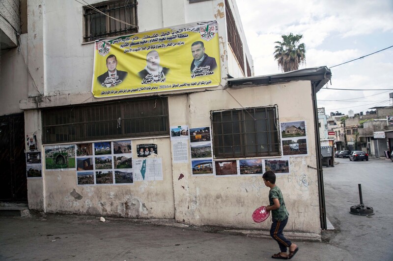 A child walks past a wall covered in posters and photos