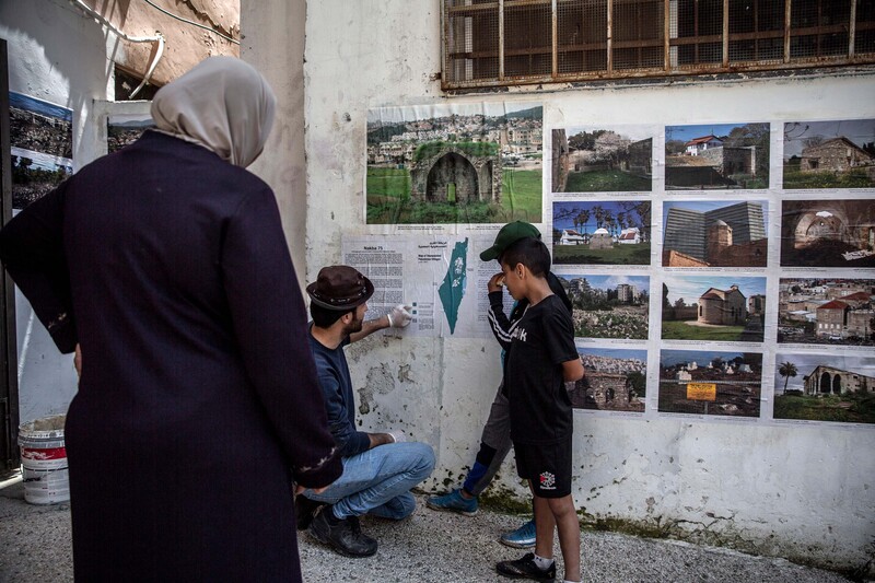 A woman looks on as a man talks to two children