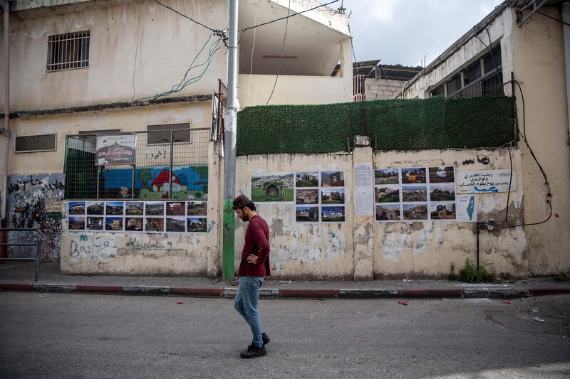 A man stands thoughtful before a wall of photos