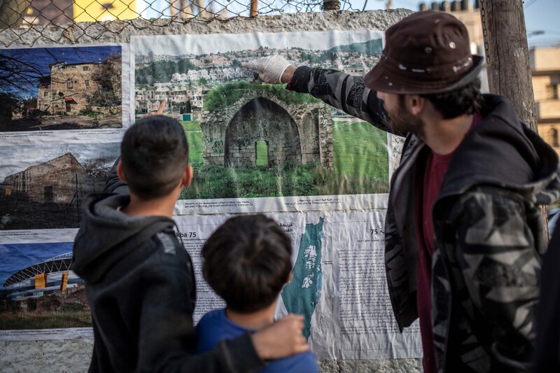 A man points at a photo with two children looking on