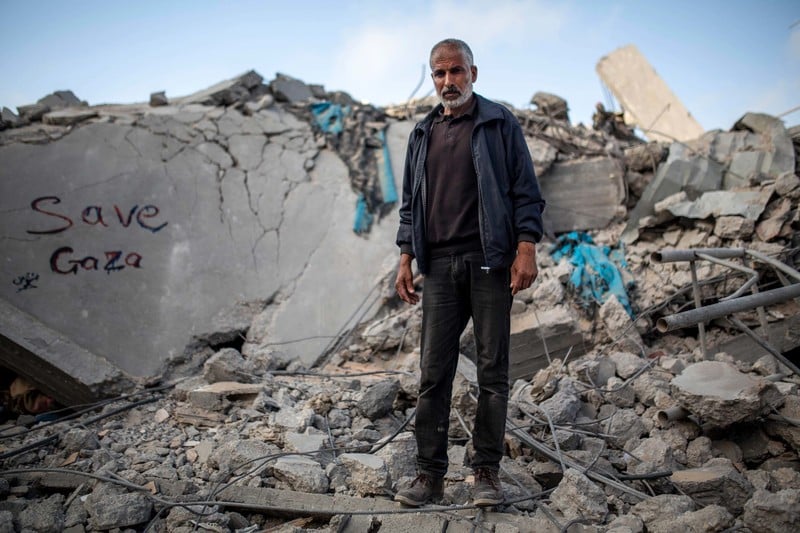 A man stands atop the rubble of a house