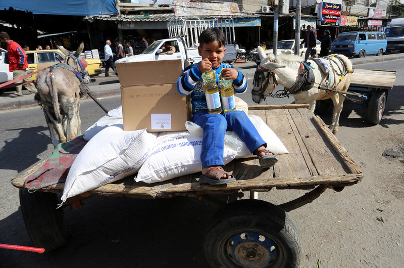 A boy sits on a cart loaded with UN food sacks