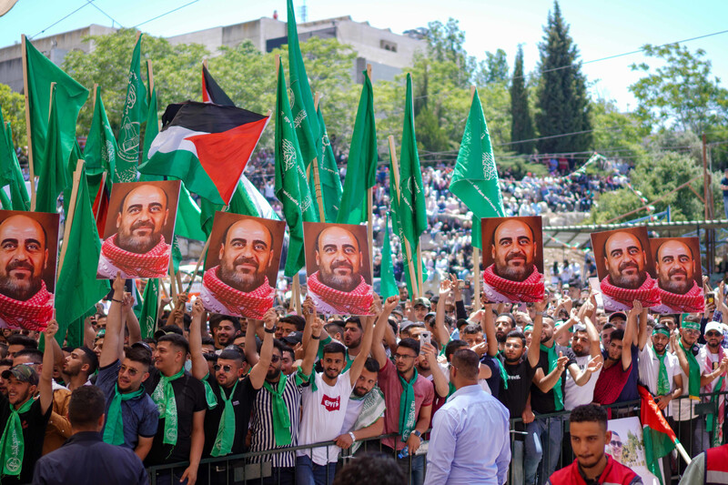 Students waving flags and holding up a portrait of a man