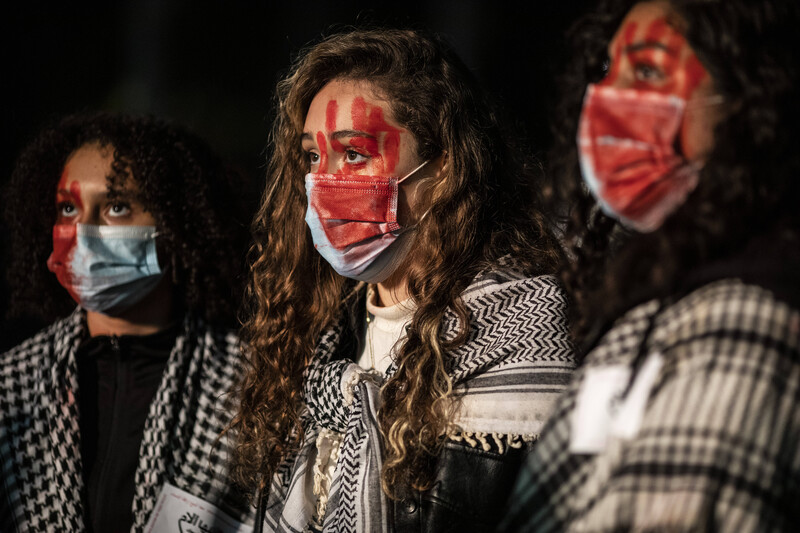 Three women with their faces painted blood red