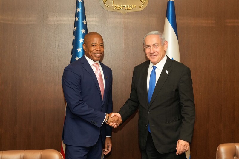 New York City Mayor Eric Adams shakes hands with Israeli Prime Minister Benjamin Netanyahu with American and Israeli flags behind them