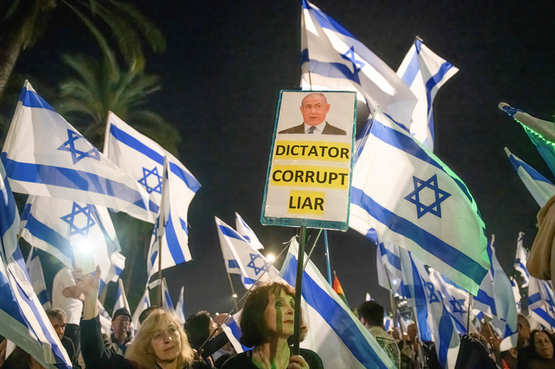 protestors wave Israeli flags and banners against Benjamin Netanyahu