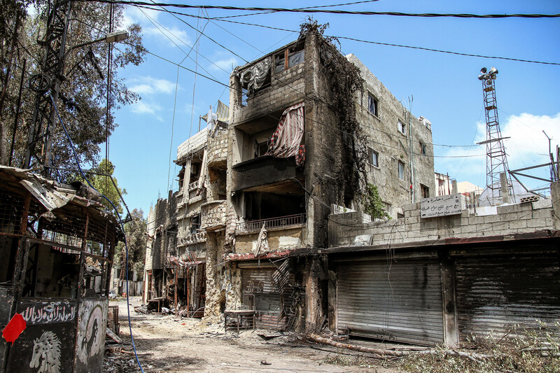 A burned-out three-story building against a blue sky