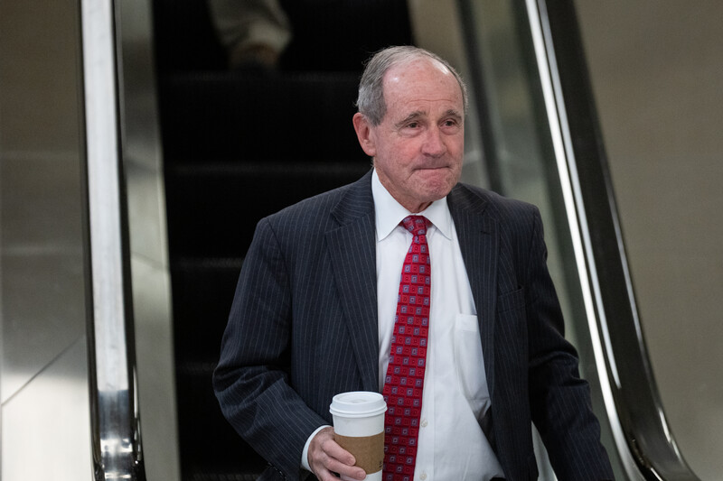 Senator Jim Risch at bottom of escalator with drink in hand