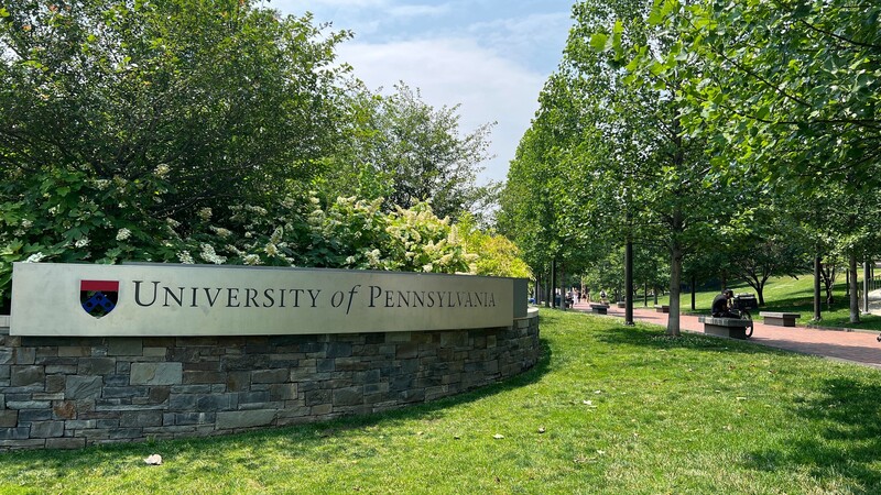 A sign with the name of the university affixed to a low stone wall.