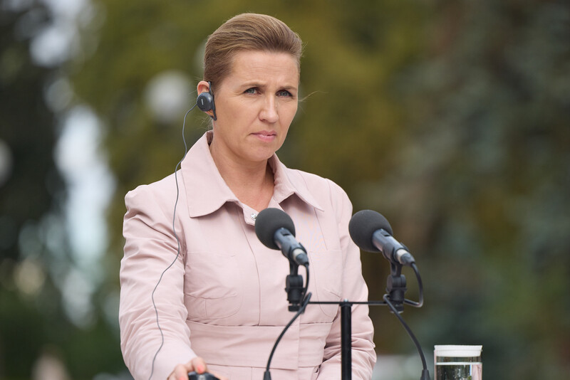 Danish PM Mette Frederiksen stands behind a microphone