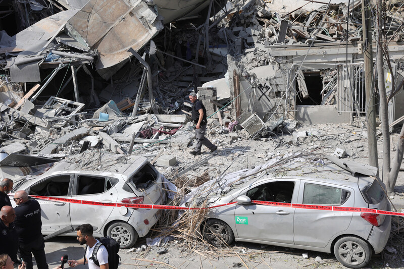 Two cars and rubble from a destroyed building are seen behind red police tape