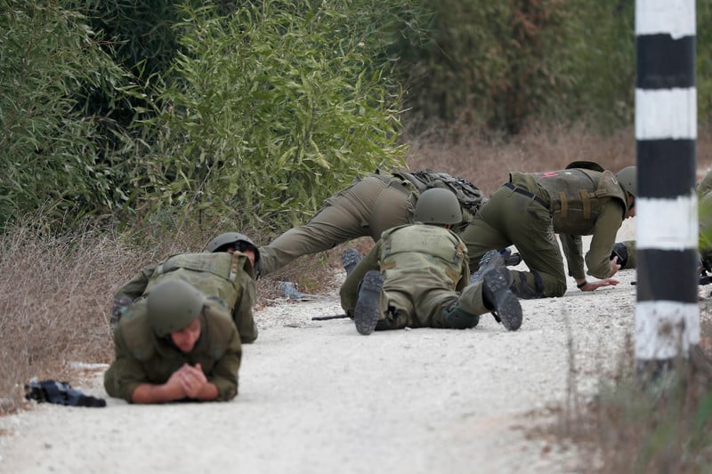 Israeli soldiers wearing military uniform and helmet lay on the ground