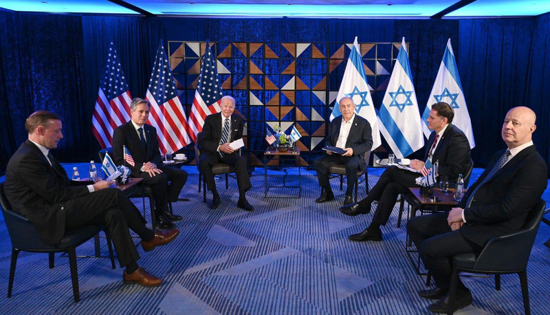 Biden and Netanyahu sit on chairs flanked by other officials with US and Israel flags behind them