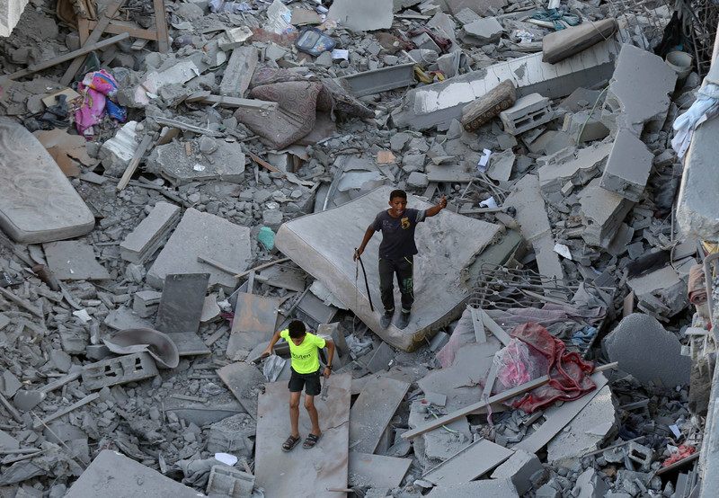 Two Palestinian children stand on rubble in al-Zahra in Gaza