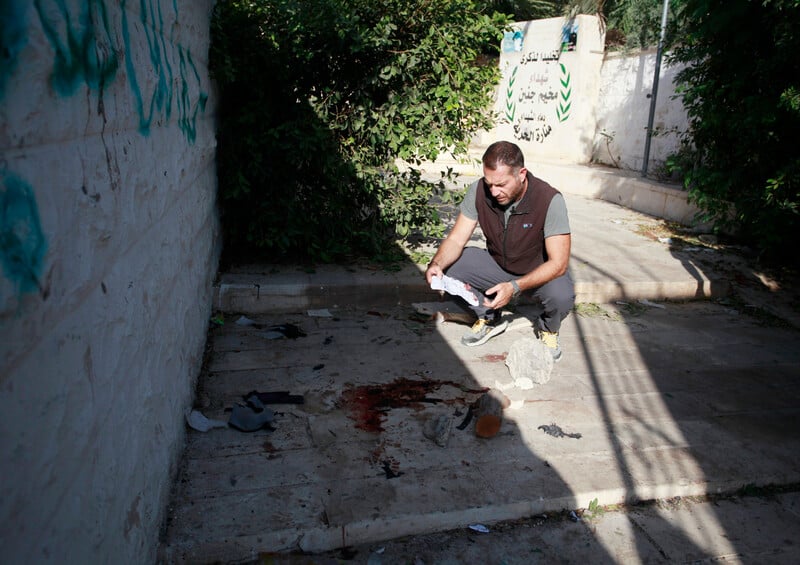 A man inspect an area splattered with blood 