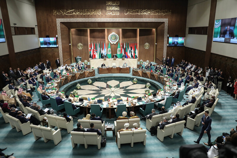 Desks are arranged in a circle in front of a number of flags at the Arab League headquarters in Cairo